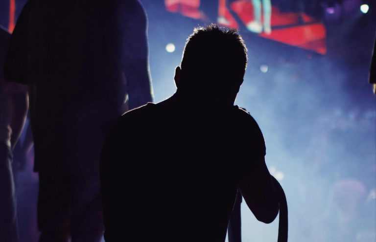 Event-Fotografie Silhouette einer Person auf einer Bühne mit buntem Licht im Hintergrund.